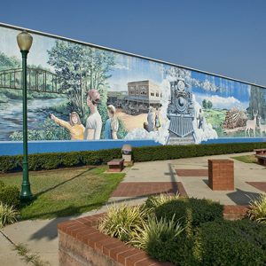 Town plaza featuring mural depicting river and iron bridge and steam train
