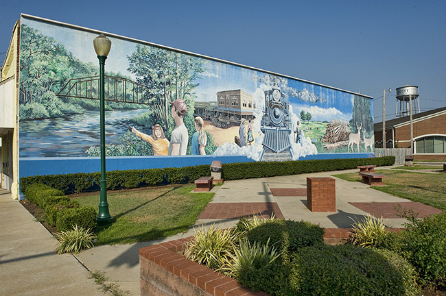 Town plaza featuring mural depicting river and iron bridge and steam train