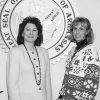 Pair of white women smiling with Arkansas State Seal on wall behind them
