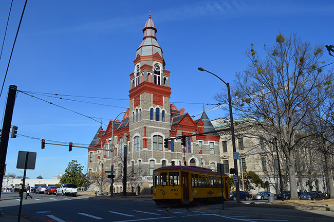 Multistory building with clock tower on city street with yellow trolley car in the foreground