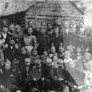 Group of white children posing for group photo outside school house