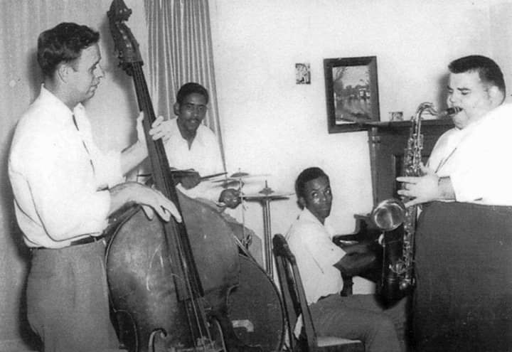 Two African-American and two white musicians playing their instruments in room