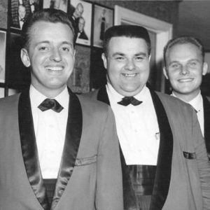 Three young white men smiling in matching suits