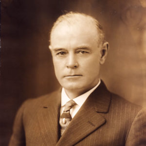 White man in suit and striped tie with pin and white shirt