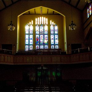 Interior of large church sanctuary with stained glass windows behind balcony
