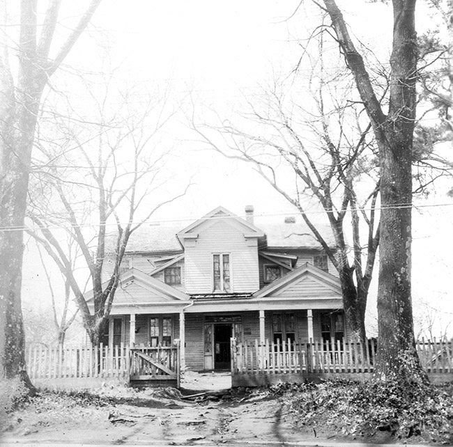 Two-story house with covered porch fence and bare trees