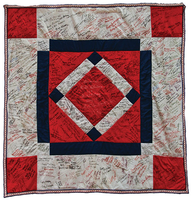 Red white and blue quilt with diamond pattern covered with signatures