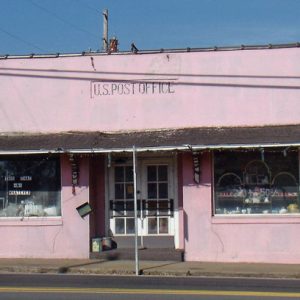 Single-story storefront building painted pink with awning