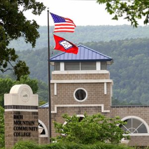 U.S. flag and state flag in front of brick building "Rich Mountain Community College"