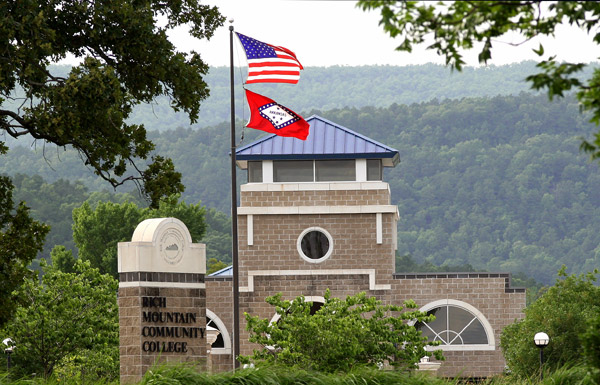 U.S. flag and state flag in front of brick building "Rich Mountain Community College"