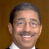 African-American man with glasses smiling in judge's robes