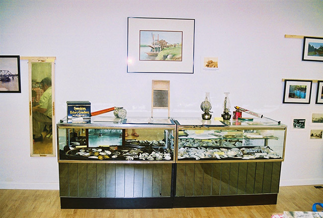 Glass display cases in room with framed pictures on the walls