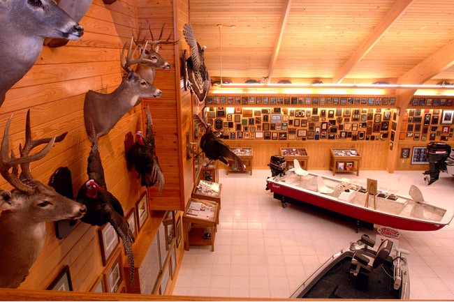 Pair of flat bottom boats in gallery room with pictures on the walls with stuffed deer heads and turkeys hanging above them