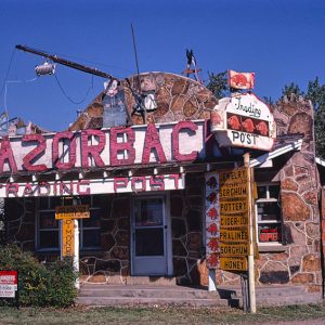 Single-story stone building with covered porch and "Razorback Trading Post" sign