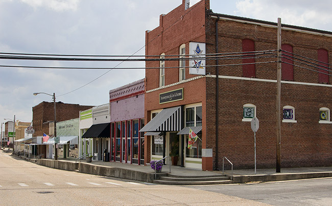 Row of multicolored brick storefronts and multistory Masonic building on street corner