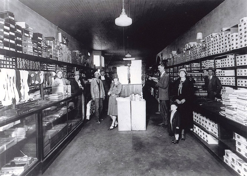 White men and women in store with glass display cases and boxes lining the wall