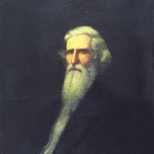Old white man with long white hair and beard in black suit