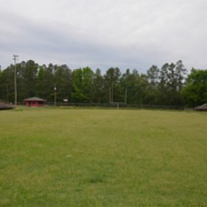 Vacant football field with bleachers on either side and goal in the background along a fence