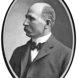 Profile view of white man with mustache in suit and bow tie in oval frame