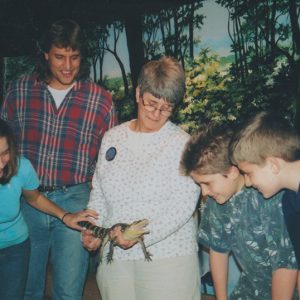 Woman showing reptile to group of children and one adult man