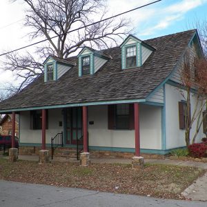 Two-story house with covered porch blue trim and five red columns