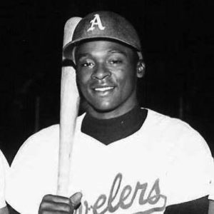smiling African-American man with hard cap and bat in uniform