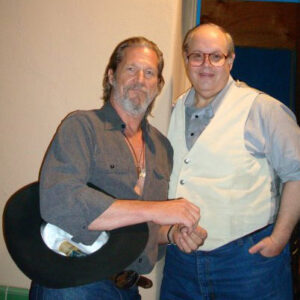 Two older white men smiling in shirts and jeans