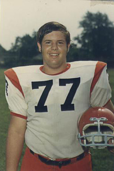 Young white man in orange and white uniform with helmet