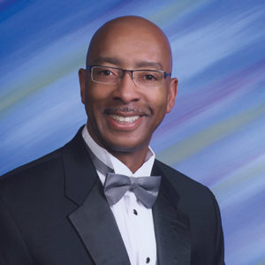African-American man with glasses smiling in suit with bow tie