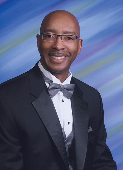 African-American man with glasses smiling in suit with bow tie