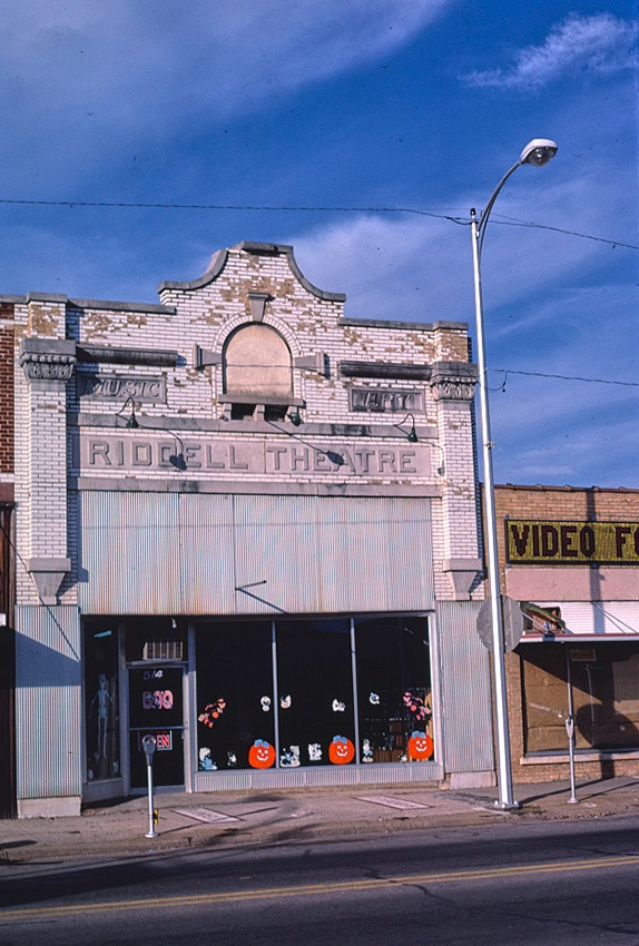 Multistory brick building with glass display windows and "Riddell Theater" written above the entrance