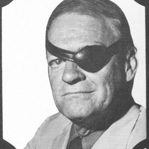 White man with black leather eye patch over left eye in suit and tie