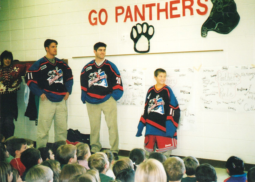 Men in hockey uniforms talking to group of boys