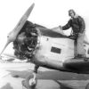 Man standing in cockpit of propeller-driven airplane