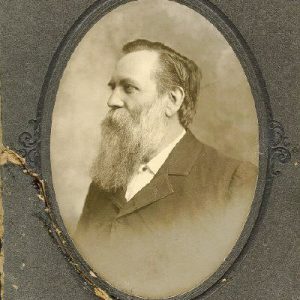 Profile view of white man with long beard in suit in oval frame