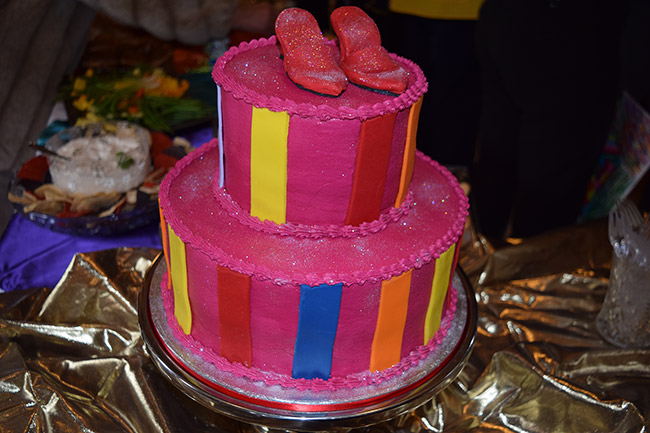 Red shoes on two-tiered cake with multicolored stripes