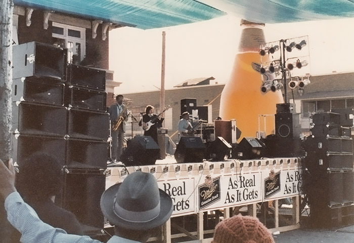 African-American man playing guitar on stage with mixed band