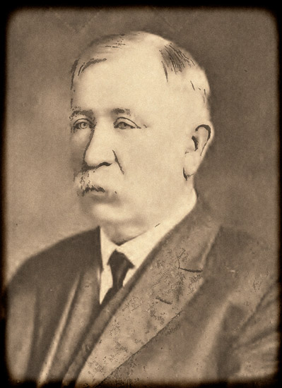 White man with white mustache in suit and tie