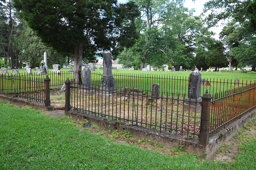 Group of monuments inside iron fence in cemetery