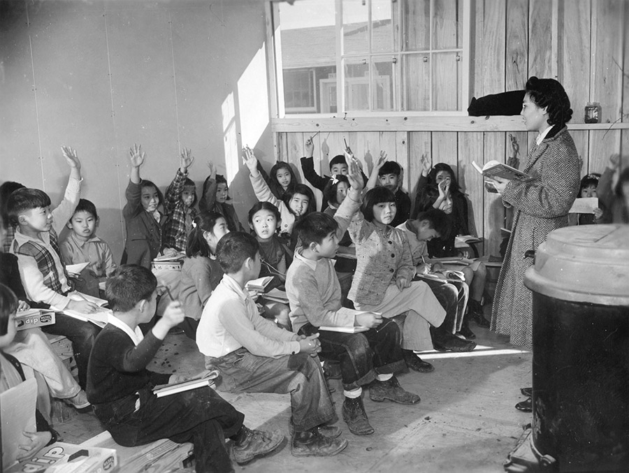 Japanese-American students and teacher in classroom with only simple benches