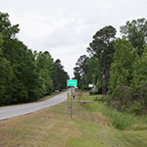 Green road sign on right side of two-lane road
