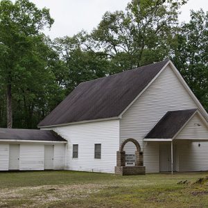 Single-story church building with white siding and covered entrance