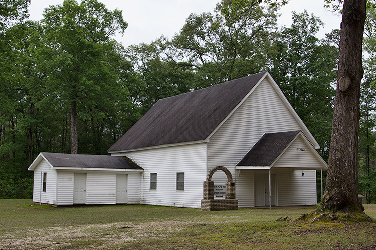 Single-story church building with white siding and covered entrance