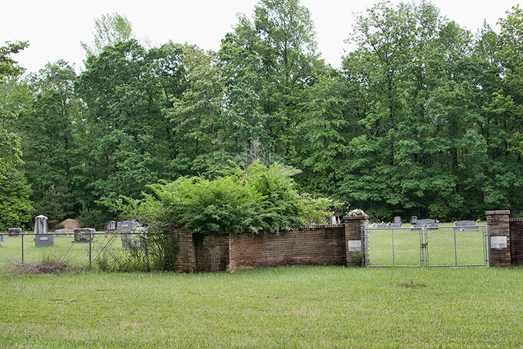 Cemetery inside fence with brick wall and gate with brick columns