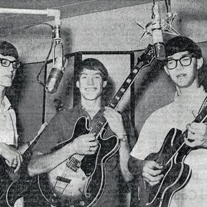 Grainy photo of three young white men with guitars and bass