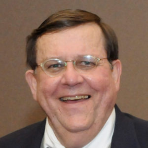White man with glasses smiling in suit and bow tie