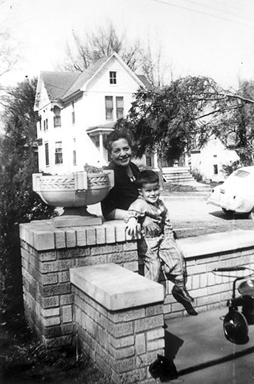 Older white woman with boy on brick wall with car and house in the background