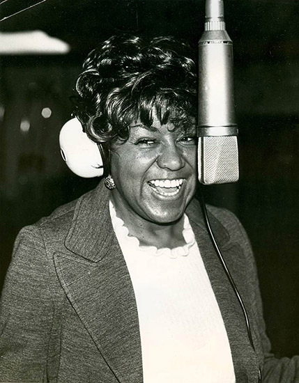 African-American woman smiling and singing into microphone