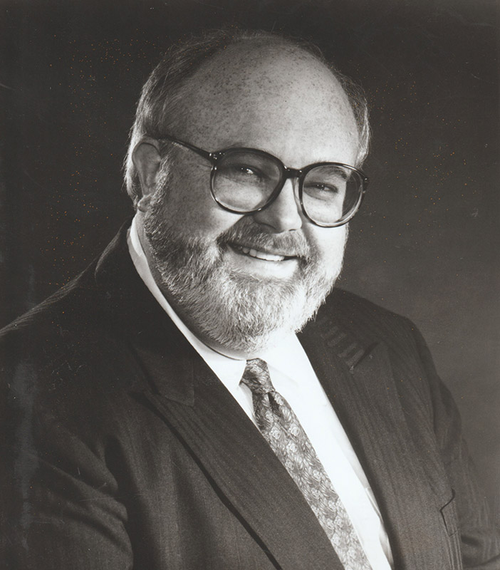Bearded white man with glasses smiling in suit and tie