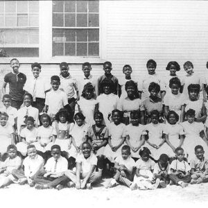 African-American man woman and children posing together outside building with wood siding